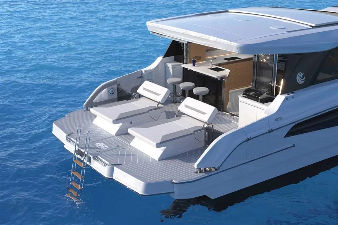 Luxury yacht deck with two loungers, stools, and kitchen area overlooking deep blue water, featuring a ladder for easy access.